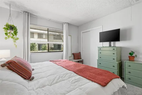 a bedroom with a bed and flat tv screen on the dresser