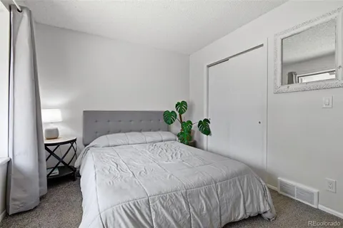 a bedroom with a bed table flowerpot and window