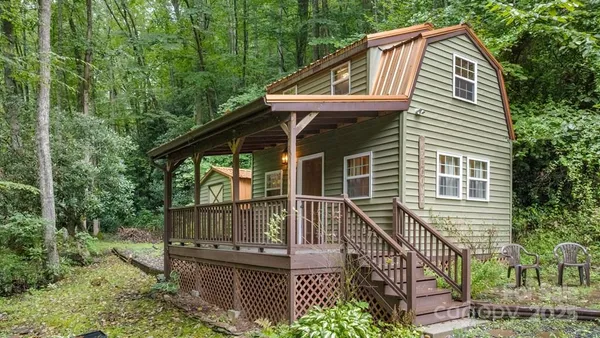 a view of house with wooden deck and outdoor seating