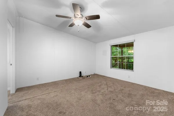 an empty room with ceiling fan and windows