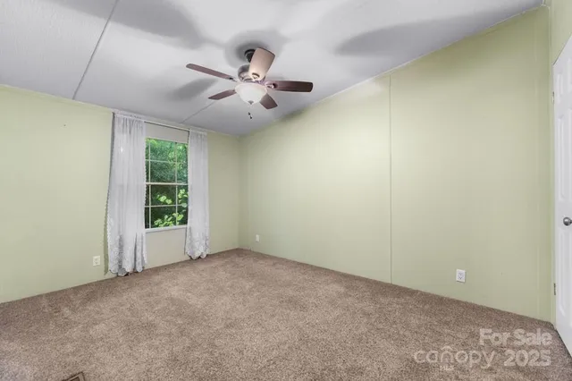 an empty room with windows and ceiling fan