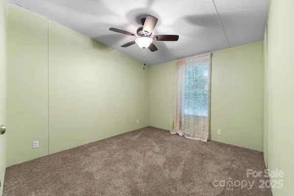 en empty room with ceiling fan and window
