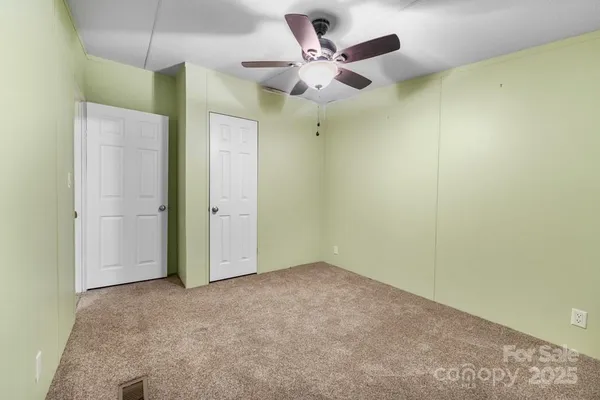 an empty room with a ceiling fan and a window