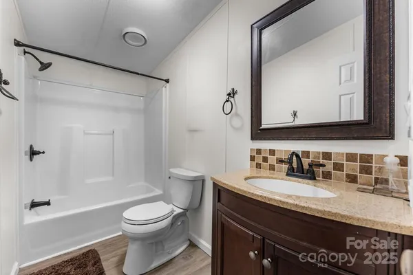 a bathroom with a granite countertop sink toilet a large mirror and shower