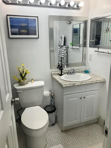 a bathroom with a granite countertop toilet sink and mirror