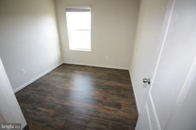 an empty room with wooden floor and window