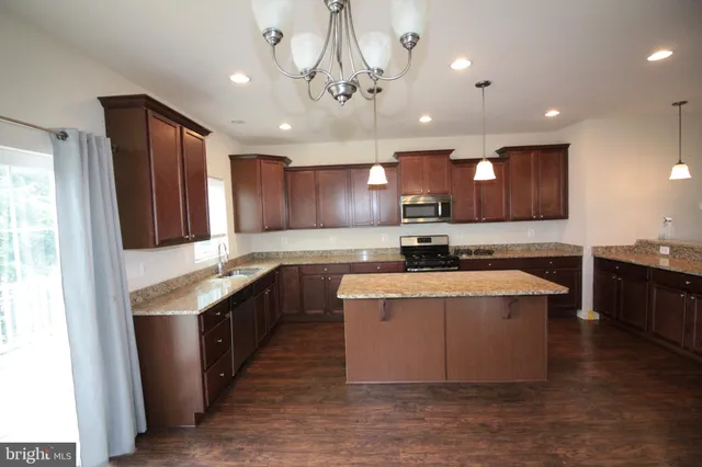 a large kitchen with a large counter top a sink and stainless steel appliances