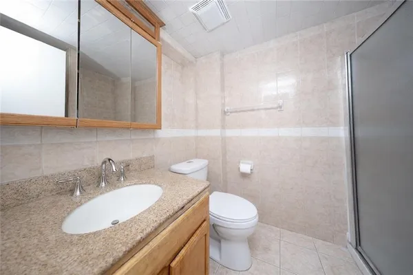 a bathroom with a granite countertop sink toilet and shower