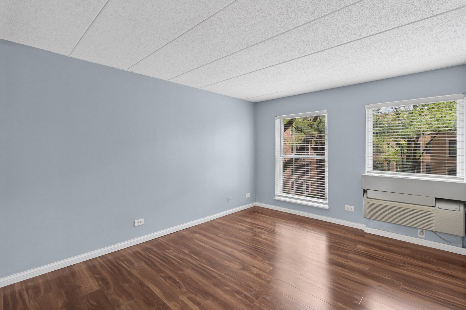 711 West Gordon Terrace, Unit 117 Chicago, IL 60613 - Photo 13 of 20 a view of an empty room with wooden floor and a window