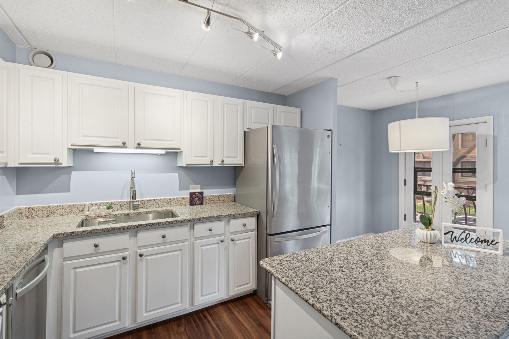 711 West Gordon Terrace, Unit 117 Chicago, IL 60613 - Photo 9 of 20 a kitchen with kitchen island granite countertop a sink cabinets and refrigerator