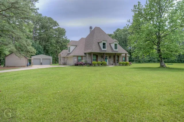 a front view of house with yard and trees in the background