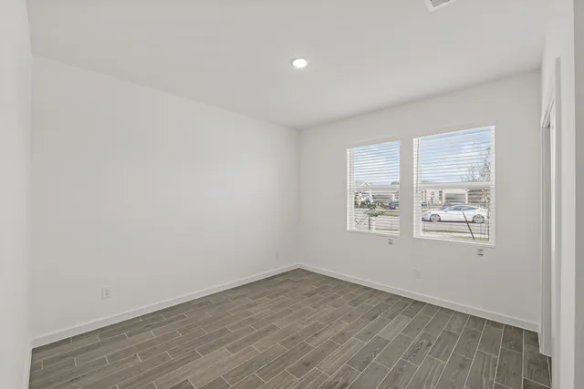 an empty room with wooden floor and windows