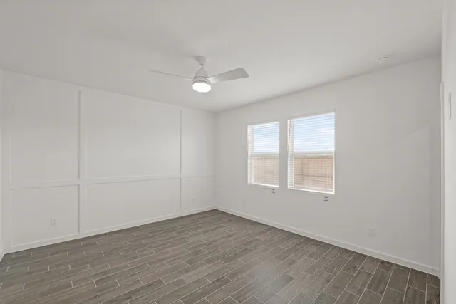 an empty room with wooden floor and windows