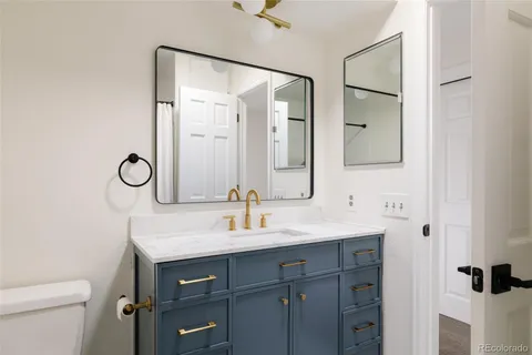 a bathroom with a granite countertop sink a toilet and a mirror