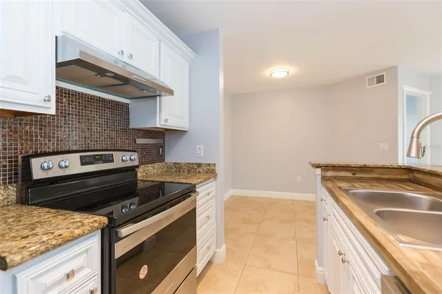 a kitchen with granite countertop a sink stove and cabinets