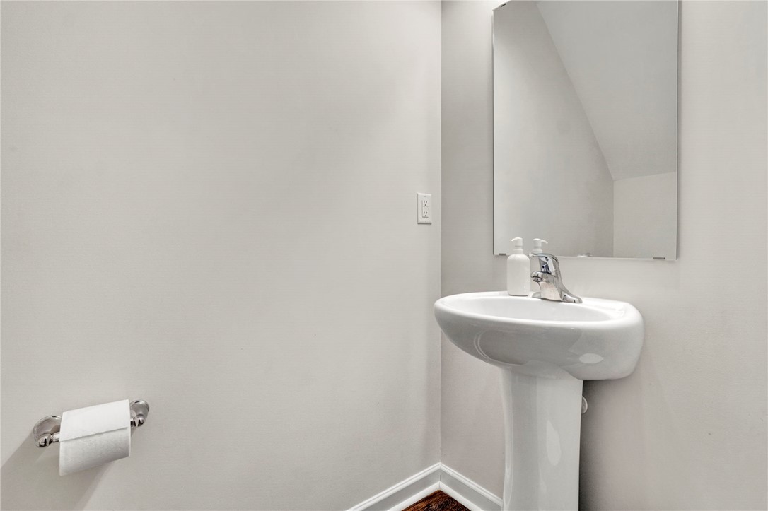 221 Samuel Street Pendleton, SC 29670 - Photo 10 of 34 This bathroom features a contemporary pedestal sink with a sleek mirror above, complemented by a simple toilet paper holder.