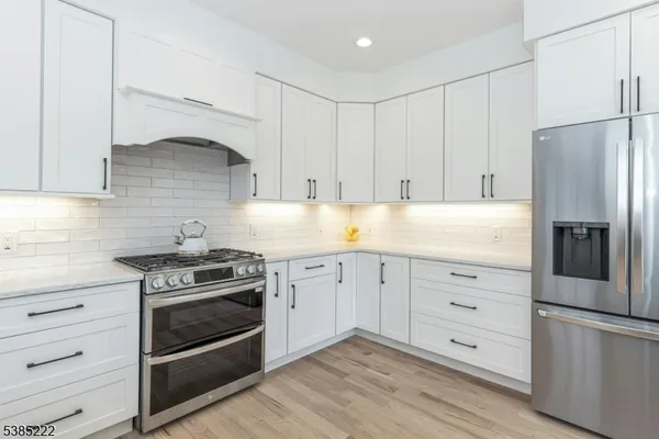 a kitchen with granite countertop white cabinets and stainless steel appliances