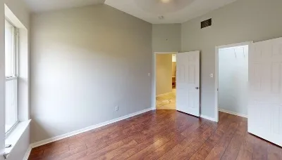 a view of an empty room with wooden floor and a window