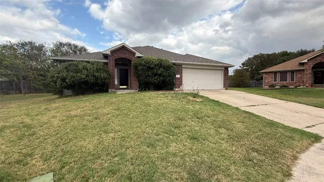 a view of a house with a yard and large tree