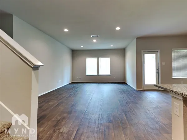 a view of an empty room with wooden floor and window