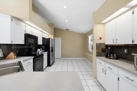 a kitchen with granite countertop a sink a stove top oven and cabinets
