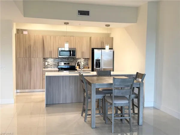 a kitchen with a table chairs a sink and a refrigerator