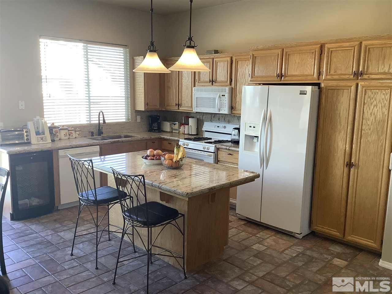 1605 Cattlemen Court Reno, NV 89521 - Photo 3 of 18 a kitchen with stainless steel appliances granite countertop a refrigerator a sink dishwasher a dining table and chairs with wooden floor