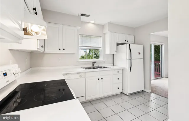 a kitchen with white cabinets and refrigerator