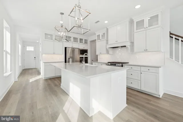 a kitchen with stainless steel appliances kitchen island hardwood floor sink and cabinets