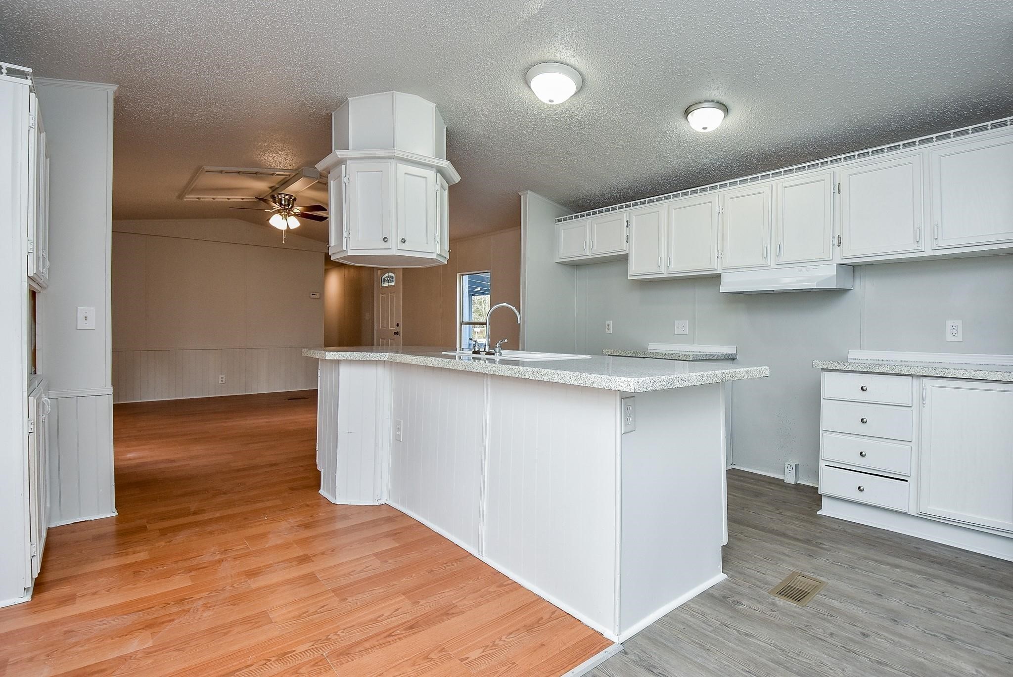 12842 Roy Harris Loop Conroe, TX 77306 - Photo 19 of 36 a kitchen with cabinets wooden floor and a sink