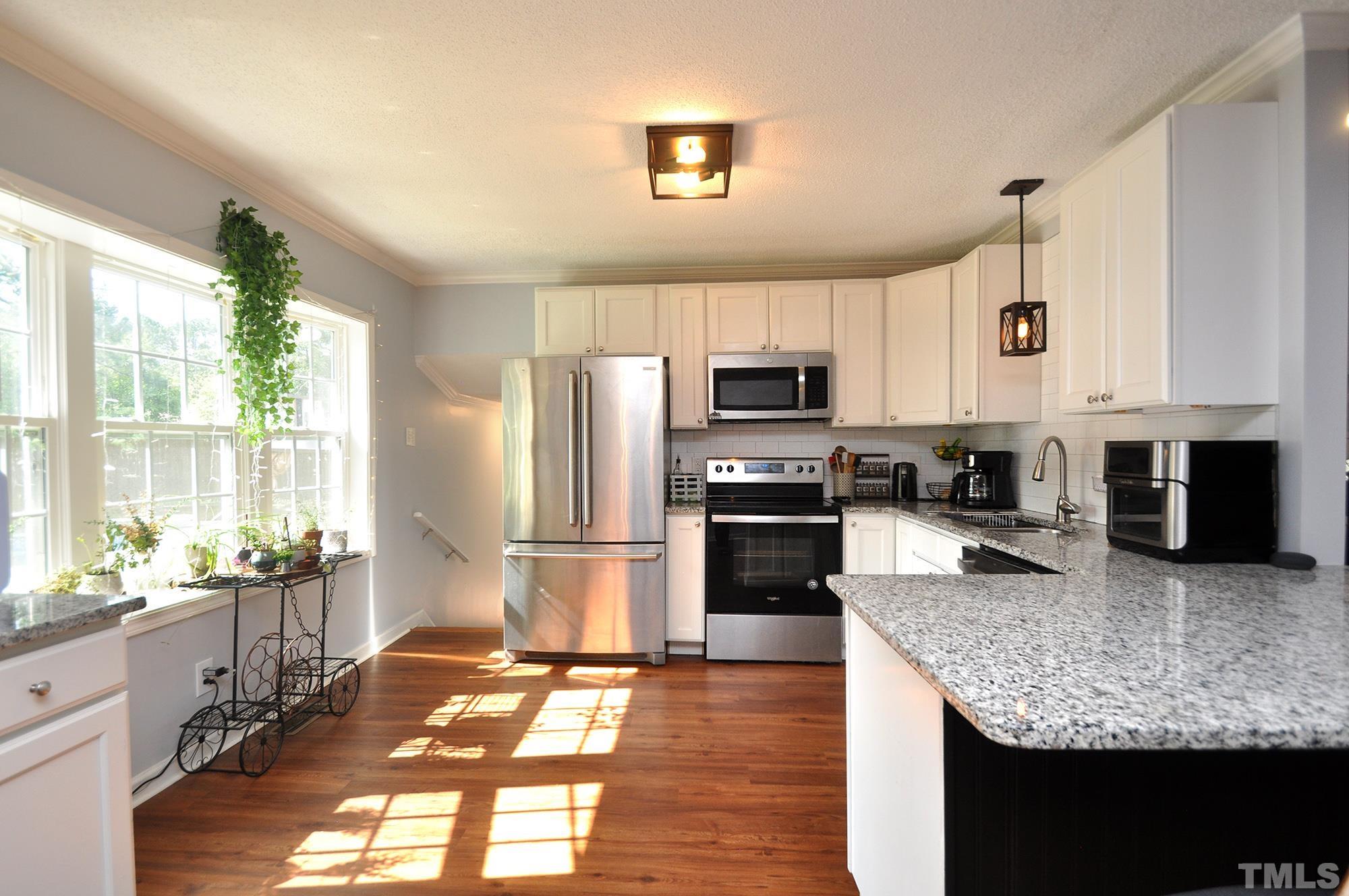 2401 Sanderford Road Raleigh, NC 27610 - Photo 8 of 31 a kitchen with stainless steel appliances granite countertop a stove top oven a sink dishwasher a refrigerator and white cabinets with wooden floor