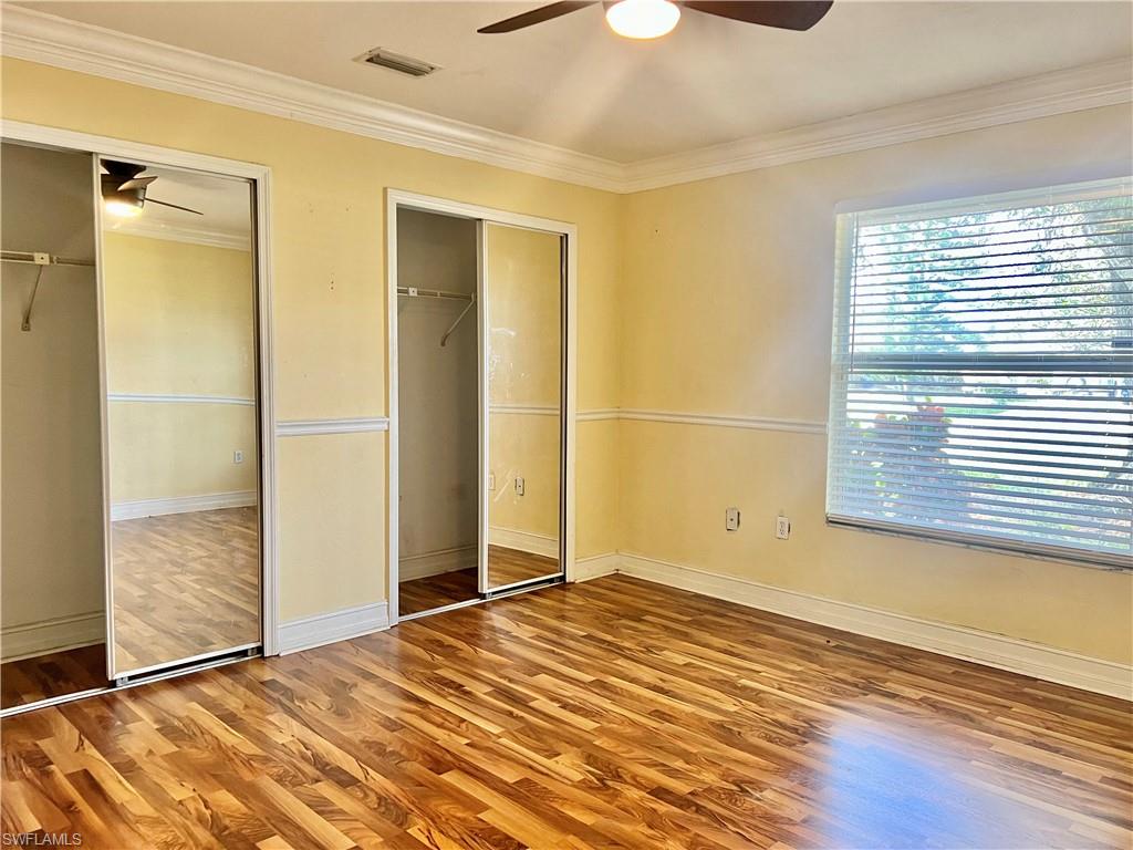18581 Tampa Road Fort Myers, FL 33967 - Photo 15 of 25 Unfurnished bedroom featuring wood-type flooring, multiple closets, ceiling fan, and ornamental molding