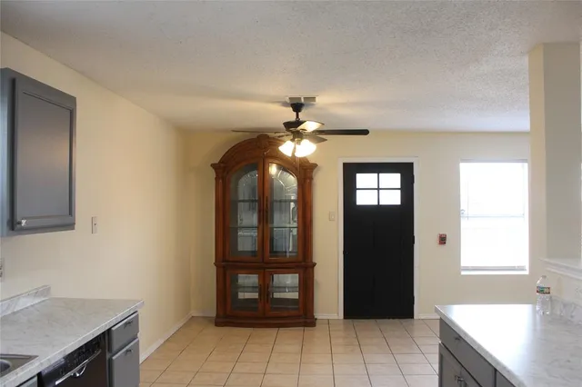 an empty room with a chandelier fan and windows