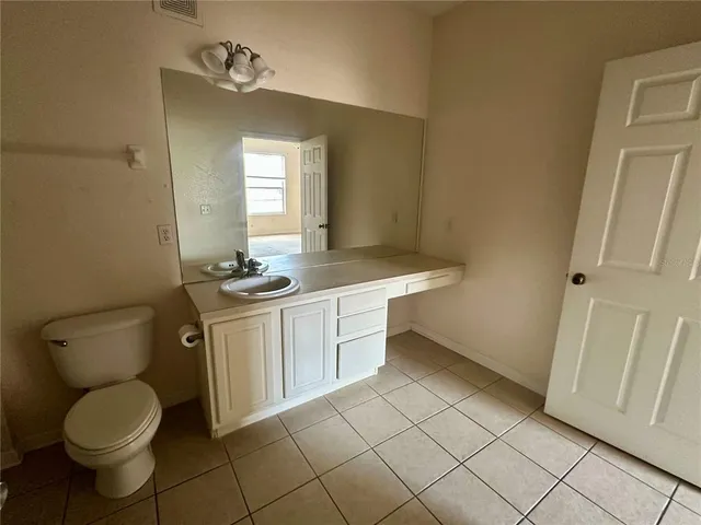 a bathroom with a granite countertop toilet sink and mirror
