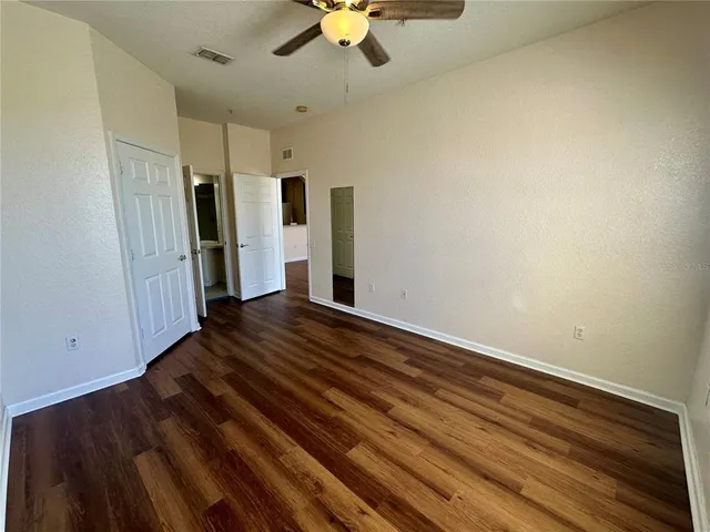 a view of empty room with wooden floor and fan