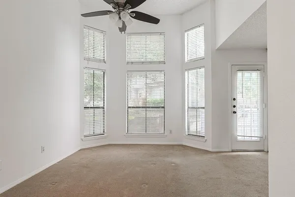 an empty room with windows and chandelier fan