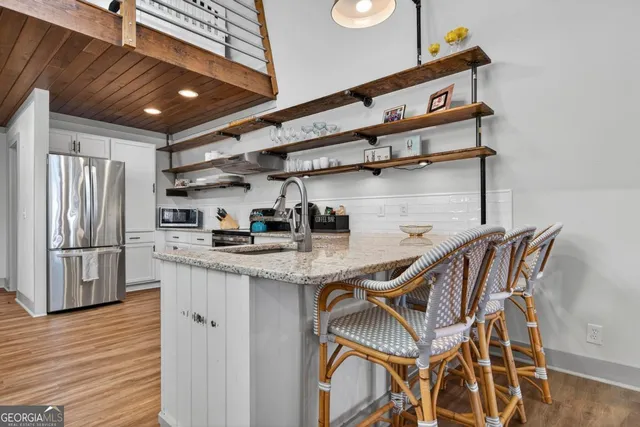 a kitchen with stainless steel appliances granite countertop a sink a stove a refrigerator and wooden cabinets