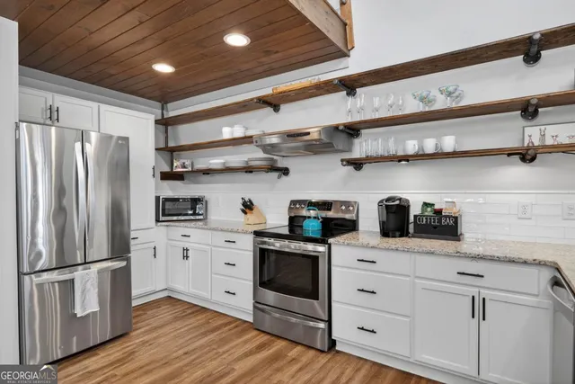 a kitchen with stainless steel appliances white cabinets and wooden floors