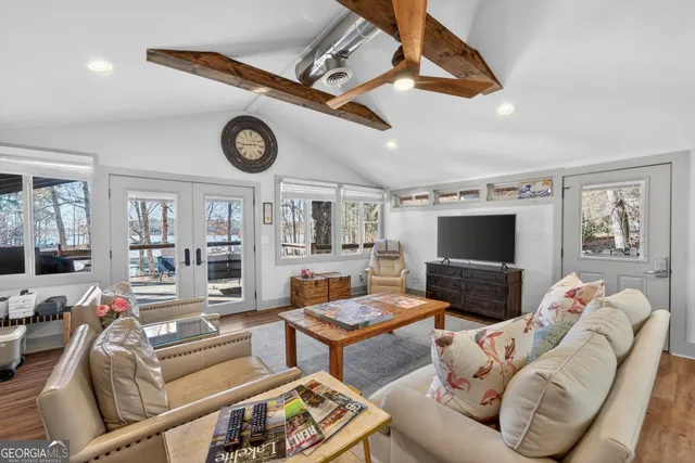 a living room with furniture a clock on the wall and a flat screen tv