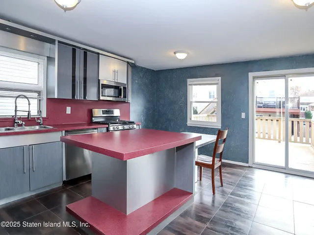 a kitchen with a stove a sink dishwasher and a dining table with wooden floor