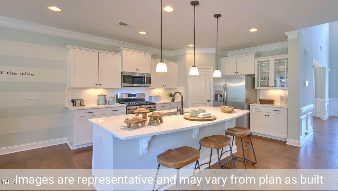 1857 Old Fields Boulevard Haw River, NC 27258 - Photo 22 of 53 a kitchen with stainless steel appliances kitchen island granite countertop a sink a stove a refrigerator and a dining table with wooden floor