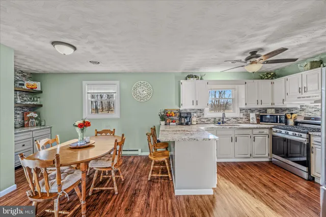 a kitchen with a dining table chairs cabinets and wooden floor