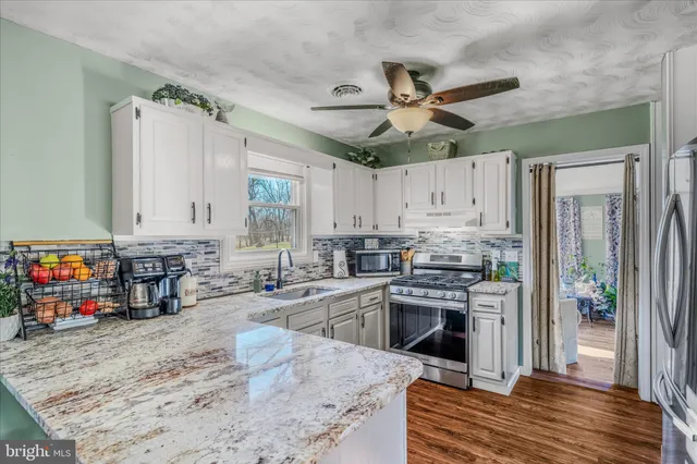 a kitchen with stainless steel appliances granite countertop a refrigerator a stove and a sink with cabinets