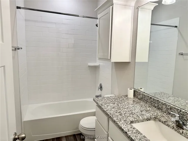 a bathroom with a granite countertop sink toilet and shower