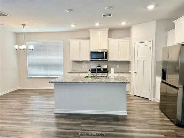 a kitchen with stainless steel appliances granite countertop a sink refrigerator and cabinets