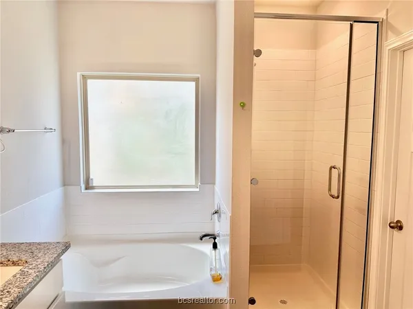a bathroom with a granite countertop window and a bathtub