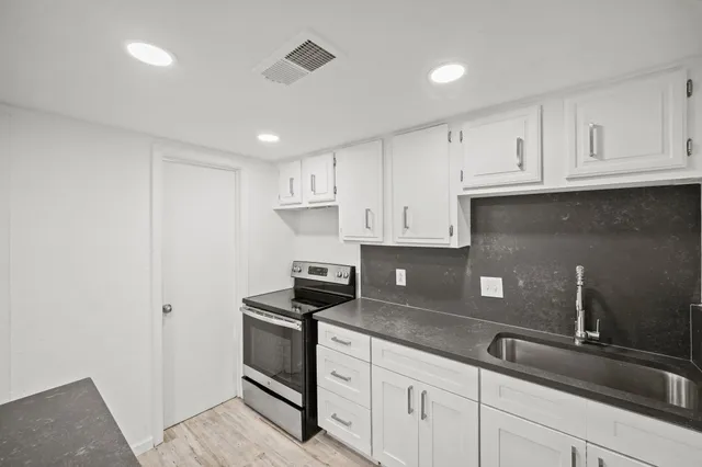 a kitchen with granite countertop white cabinets and a sink