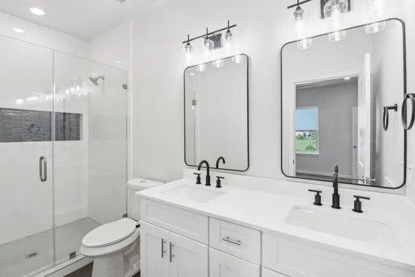 a bathroom with a double vanity sink toilet and shower