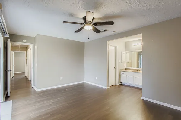 an empty room with wooden floor a ceiling fan and windows