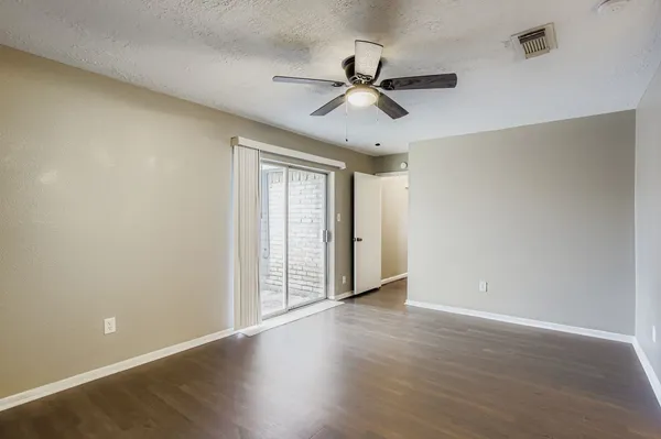 an empty room with wooden floor fan and windows